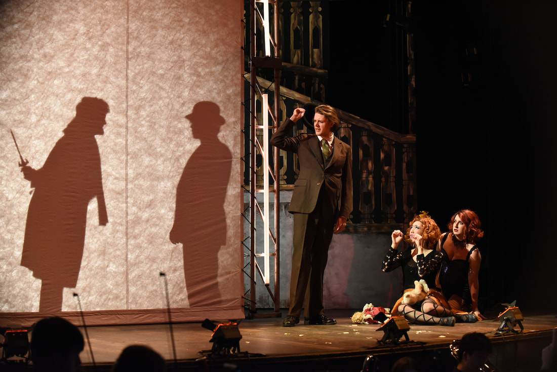 A shadow image of a man holding a knife behind his back standing in front of another man