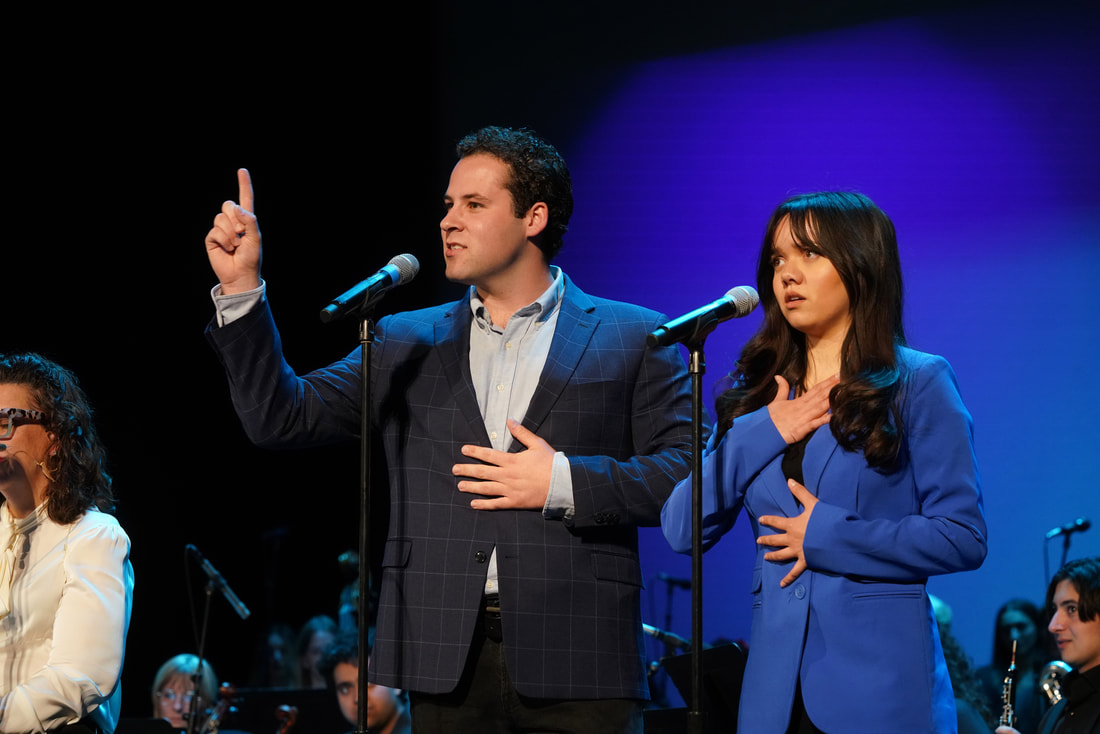 A man and a woman singing into microphones on stands