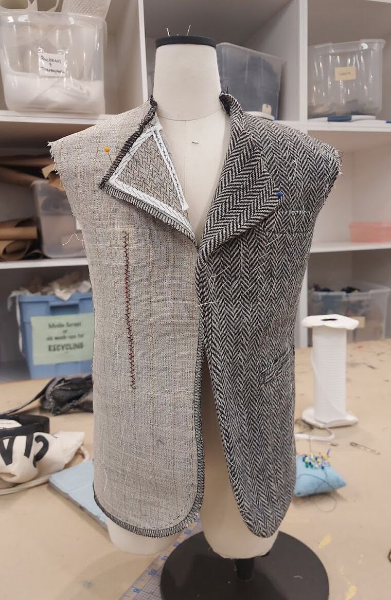 Front of a half-scale hand tailored suit jacket without sleeves or a collar, half with wool and half with just the canvas